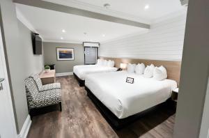 una camera d'albergo con due letti e una sedia di Colonial Hotel & Suites a Grand Bend