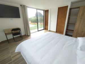 a large white bed in a room with a large window at Cabaña Estancia Primavera in Guatapé