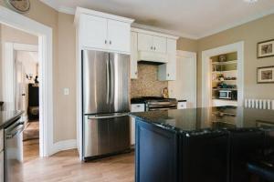 a kitchen with a stainless steel refrigerator and white cabinets at Harvard House-The Gathering Place in Waltham
