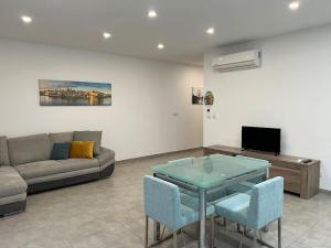 a living room with a couch and a glass table at Sea side view 2 bedroom apartment with terrace Beppe`s apartment in St Paul's Bay