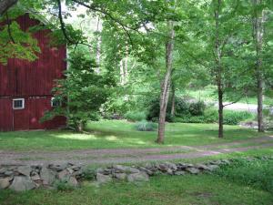 a path next to a red barn and trees at Private setting on country farm near Rhinebeck in Clinton Corners