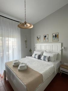a bedroom with a large white bed with two towels on it at Gaia Apartments in Hanioti