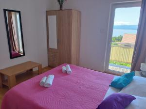 a bedroom with a pink bed with slippers on it at Apartments Tonka in Bol