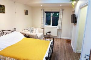 a bedroom with a bed and a couch at Holly Tree Hideaway in Milton Keynes