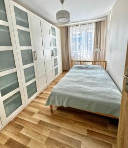 sypialnia z łóżkiem i drewnianą podłogą w obiekcie Nowoczesny apartament blisko centrum Warszawy z podziemnym garażem i bardzo szybkim WiFi oraz balkon w mieście Ząbki