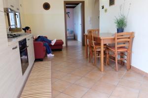 a woman sitting on a couch in a kitchen with a table at Appartamento in villa al mare in Siracusa