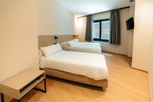 Un dormitorio con dos camas y una ventana. en Mouritz Rooms, en Negreira