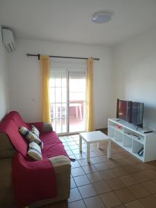 ein Wohnzimmer mit einem Sofa und einem TV in der Unterkunft Islantilla Club Golf in Huelva