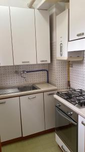 eine Küche mit weißen Schränken und einer Spüle und einem Herd in der Unterkunft La casa al mare in Grottammare + 4 Fotos