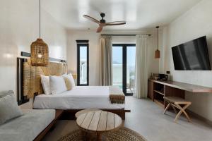 a bedroom with a bed and a couch and a tv at Boho Sapiens Sea View in Adamas