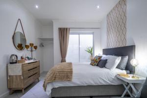 a bedroom with a bed and a desk and a window at Cosy and Central in Claremont in Cape Town