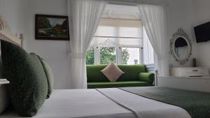 a living room with a green couch and a window at Adelfia Hotel in Alaçatı