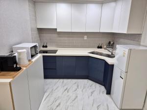 a kitchen with blue cabinets and a white refrigerator at JW's Bukhansan Healing Stay Ill in Seoul