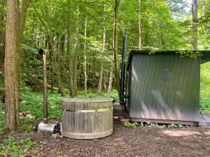 a small trailer and a barrel in the woods at Tiny house u Dlouhé řeky in Buchlovice