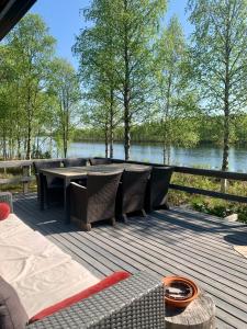 a wooden deck with chairs and a table and water at Authentic Log Cottage with Hot Tub in Ranua