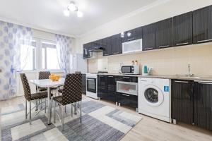 a kitchen with a table and a washing machine at Просторные апартаменты в центре in Taldykolʼ