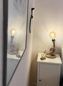 ein Badezimmer mit einem Spiegel und einer Lampe an einem Waschbecken in der Unterkunft Duhnentraum direkt am Sandstrand, Zentrum, Balkon, Meerblick, Parkplatz, Aufzug, Wlan Netflix uvm in Cuxhaven