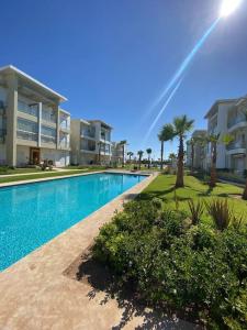 - une piscine en face d'un bâtiment avec des palmiers dans l'établissement CASA BAY BEACH OMK 3, à Sidi Rahal