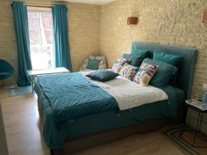 een slaapkamer met een bed met blauwe lakens en kussens bij Chambres d’hôtes de l’Ancienne Auberge in Thaon