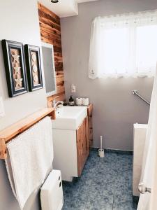 La salle de bains est pourvue d'un lavabo, de toilettes et d'une fenêtre. dans l'établissement À Bon Port, à Percé