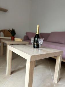 a wooden table with a bottle of champagne and a glass at Ema Rooms in Novi Vinodolski