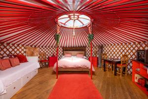 Casa Rural Alba Montis في غويخار سييرا: غرفة نوم مع خيمة حمراء مع سرير وسجادة حمراء