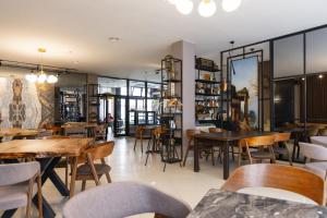 普里茲倫的住宿－Denis Hotel，餐厅设有木桌、椅子和窗户。