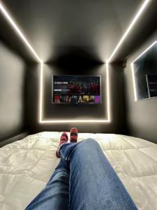 eine Person, die auf einem Bett mit den Füßen auf einem Fernseher liegt in der Unterkunft Hotel Joy Cll 85 in Bogotá