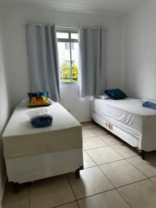two beds in a room with a window at Apartamentos da Thay in Campina Grande
