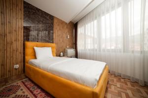 a bedroom with a large bed and a large window at Denis Hotel in Prizren