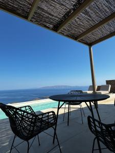 een patio met een tafel en stoelen en de oceaan bij Thermyes Villas 3 in Kithnos