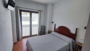 ein Schlafzimmer mit einem Bett und einem großen Fenster in der Unterkunft Hostal Jadraza in Zahara de los Atunes