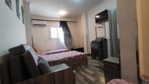 Habitación pequeña con 2 camas y TV. en فندق أجياد Agyad Hotel, en Asiut