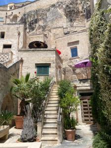 a stone building with stairs and a purple umbrella at Maison d'Ax in Matera