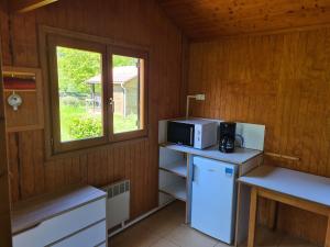 a kitchen with a microwave and a refrigerator and a window at Les Chalets Guinguette in Capdenac-Gare