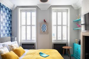 Dream Stays Bath - Kingsmead Street في باث: غرفة نوم بها نافذتين وسرير ذو بطانية صفراء