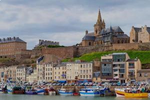 eine Gruppe von Booten, die in einem Hafen mit einem Schloss angedockt sind in der Unterkunft Beach house in Gouville-sur-Mer