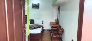 Camera con letto, scrivania e sedie. di Hill Inn Rooms an HomeStay a Ooty