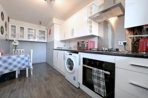 cocina con armarios blancos, lavadora y secadora en 3 BEDROOM FLAT IN CENTRAL LONDON - REGENTS PARK / BAKER ST, en Londres