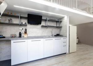 cocina con armarios blancos y TV en la pared en La tua casetta, en Ascoli Piceno