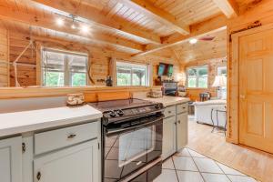 cocina con paredes de madera y horno con fogones en Smoky Mountain Log Cabin Close to Rafting!, en Hartford