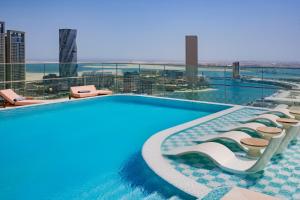 una piscina con tumbonas en la parte superior de un edificio en Conrad Bahrain Financial Harbour en Manama