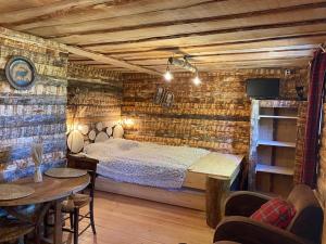 Un dormitorio con una cama en una pared de ladrillos. en La Cabane trappeur, en Gravières