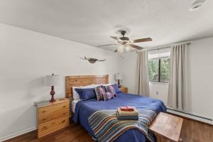 Schlafzimmer mit einem blauen Bett und einem Deckenventilator in der Unterkunft Rustic Mountain Getaway~Golf~Skiing~Hiking in Angel Fire