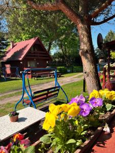 Centrum Wypoczynkowe Karman في غدانسك: مقعد الحديقة والزهور أمام شجرة