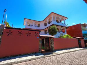 uma casa com uma cerca vermelha em frente em Hotel Galapagos Suites B&B em Puerto Ayora