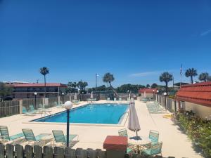 ein Pool mit Liegestühlen und Sonnenschirmen in einem Ferienresort in der Unterkunft A1A Brownwaves in St. Augustine
