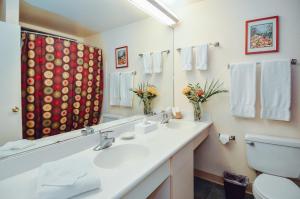 a bathroom with a sink and a toilet and a mirror at Banyan Harbor Resort in Lihue