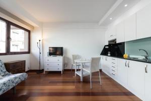 eine Küche mit weißen Schränken und einem Tisch mit Stühlen in der Unterkunft Loft moderno y cómodo a un minuto de Las Canteras in Las Palmas de Gran Canaria
