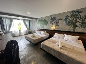 una camera con due letti e un dipinto sul muro di Eco Hotel La Colina Mirador a Quimbaya